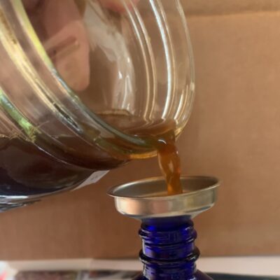 A brown liquid getting poured into a blue bottle.