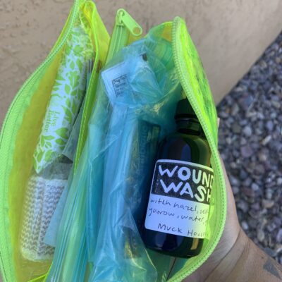 A neon green bag containing a bottle of wound wash and other first aid supplies.